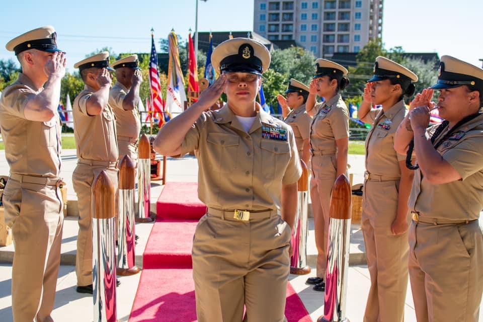 Kristy Davis saluting during her Chief Petty Officer pinning ceremony with sideboys saluting in full dress uniform